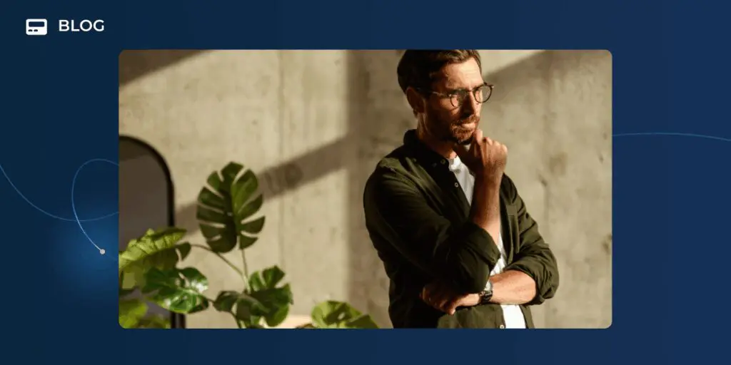 A man with glasses stands indoors in sunlight, thoughtfully resting his hand on his chin. Green leafy plants are beside him as he considers revenue growth strategies. The image is framed by a dark blue graphic with "BLOG" in the corner.