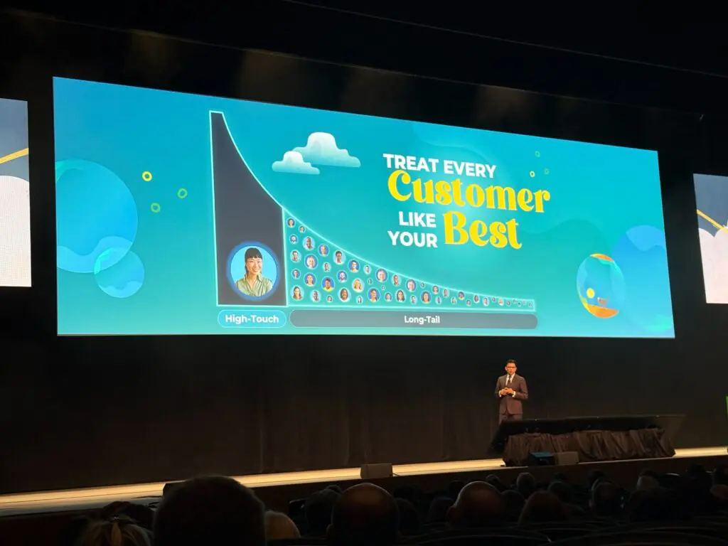 A speaker stands on stage at Pulse Europe 2025, in front of a large screen displaying a graph and the message, “Treat every customer like your best,” setting the tone for Retention as a Service. The audience watches intently in a dark auditorium.