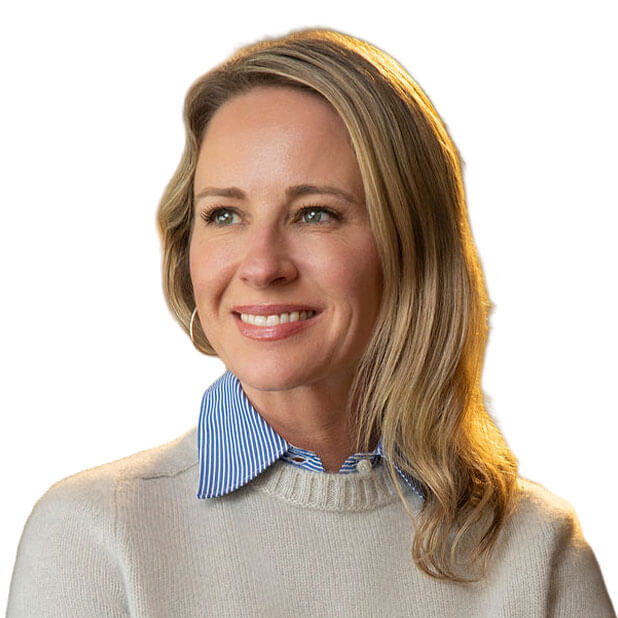 Portrait of Marilee Bear, a woman with long blonde hair. She is smiling and looking to her left. She is wearing a light-colored sweater over a blue and white striped collared shirt. The background is white.