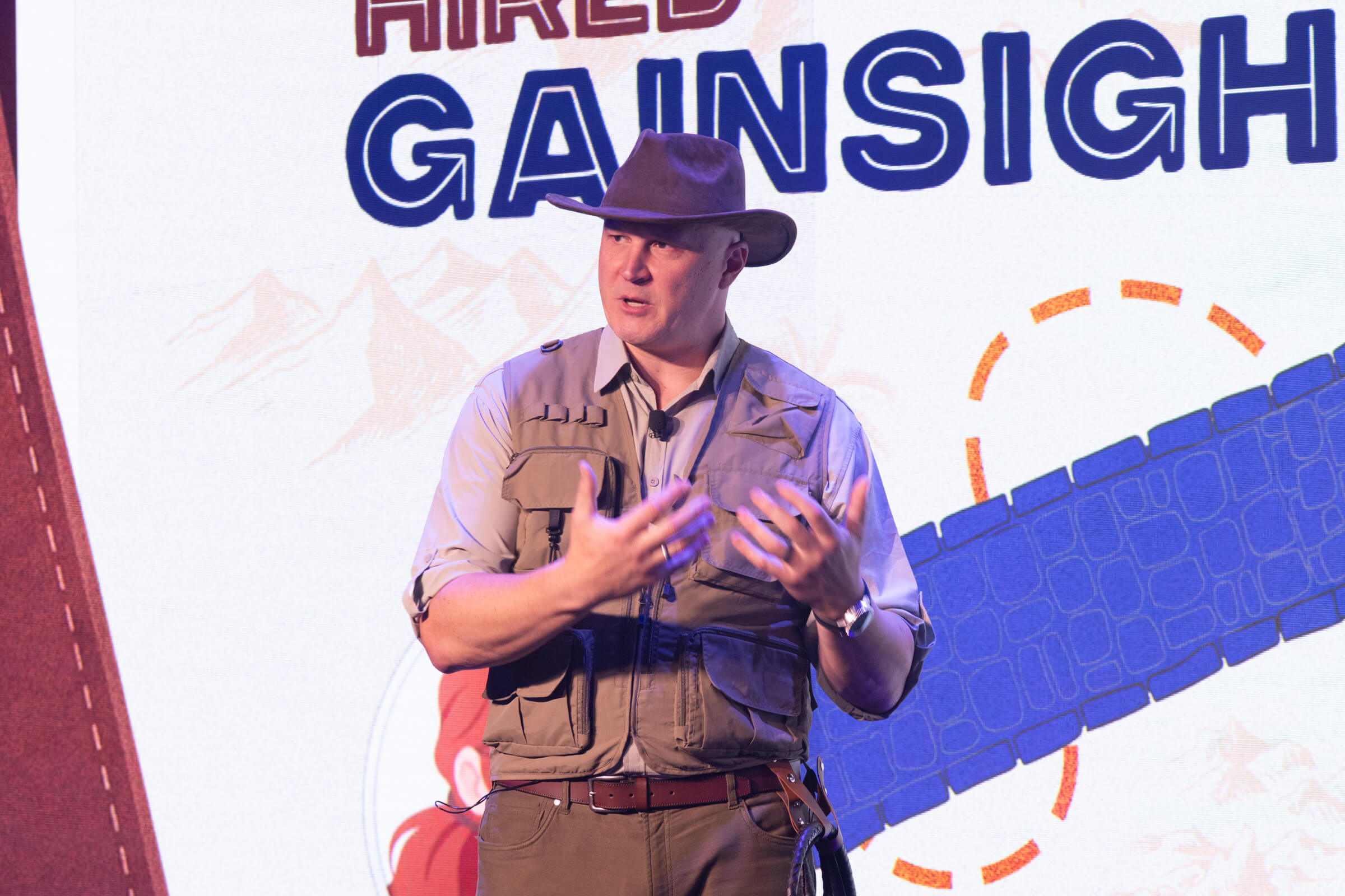 A man in a safari-style vest and hat gestures while discussing the agentic economy on a stage in front of a Gainsight Pulse Europe 2026 branded backdrop.