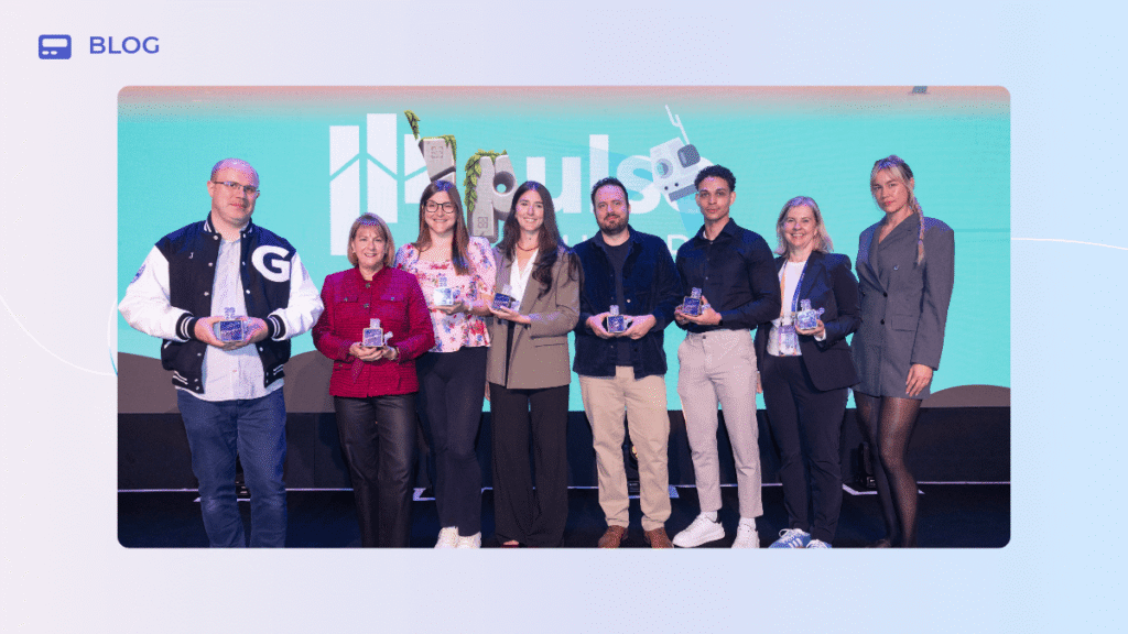 Seven people stand in a row on a Pulse Europe stage in front of a turquoise branded backdrop, each holding a GameChangers glass award.