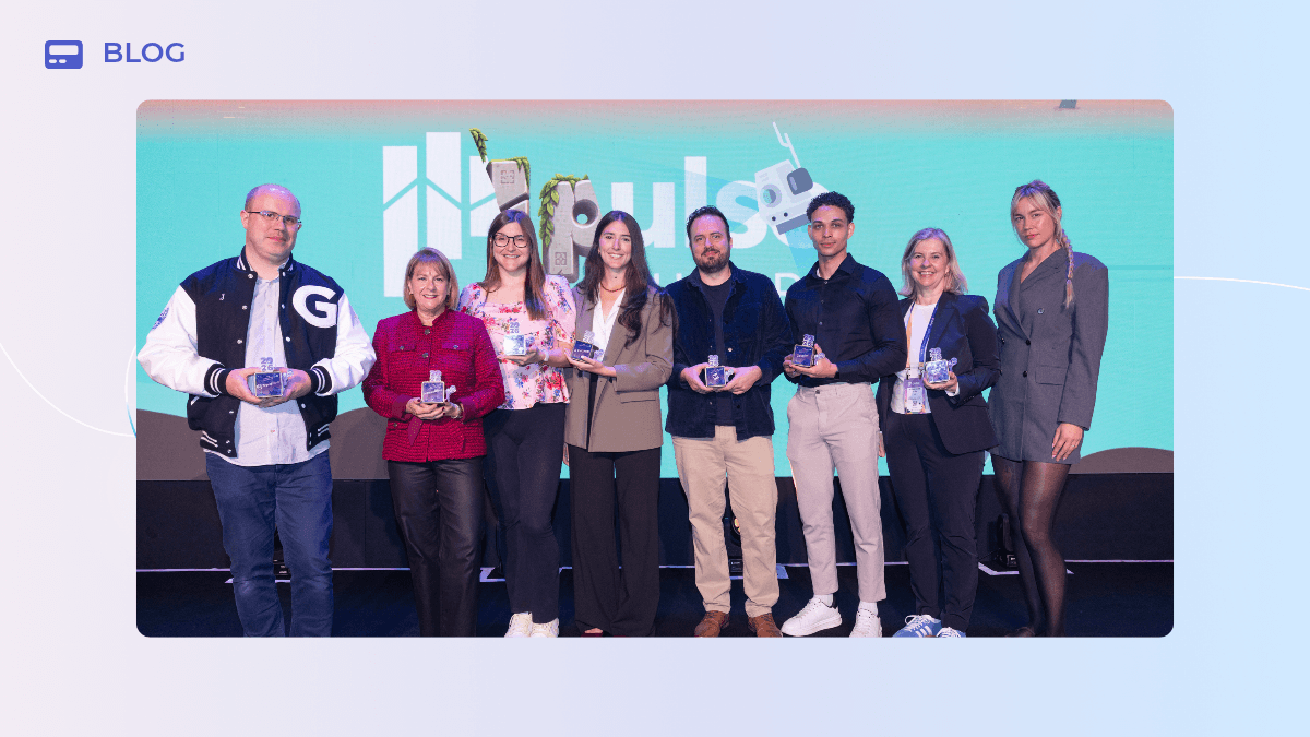 Seven people stand in a row on a Pulse Europe stage in front of a turquoise branded backdrop, each holding a GameChangers glass award.