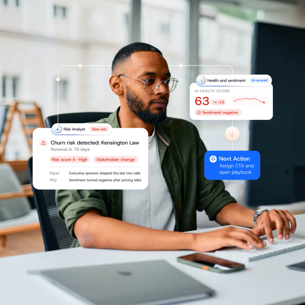 A professional working at a desk with a Gainsight CS dashboard overlaid to display churn risk, health scores, and suggested next actions.